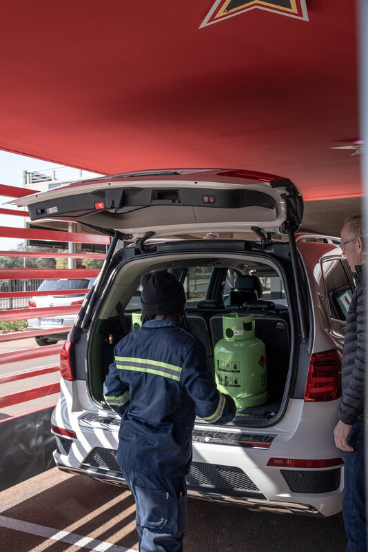 Staff member loading gas cylinder into vehicle